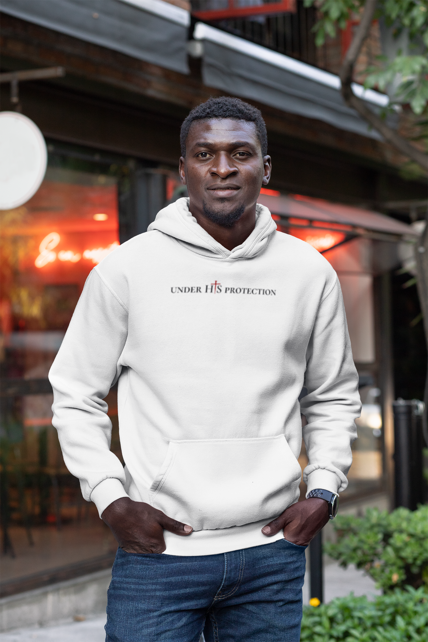 Person wearing “Under His Protection” hoodie by MyCreed with scripture design on front.